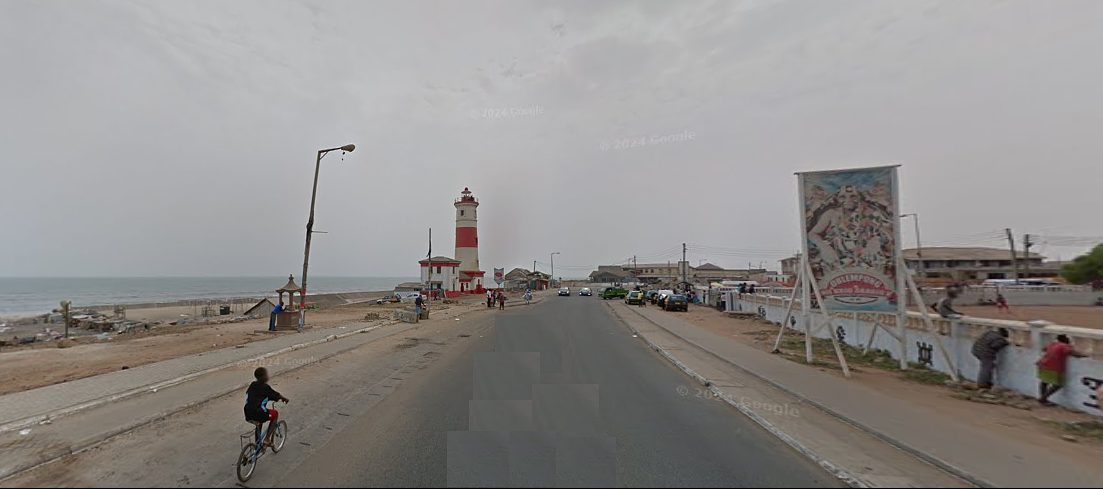 A boy rides his bike towards Jamestown in Accra. On the left is the beach.