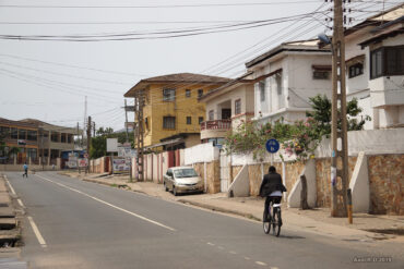 a cyclist rides through a street in Accra