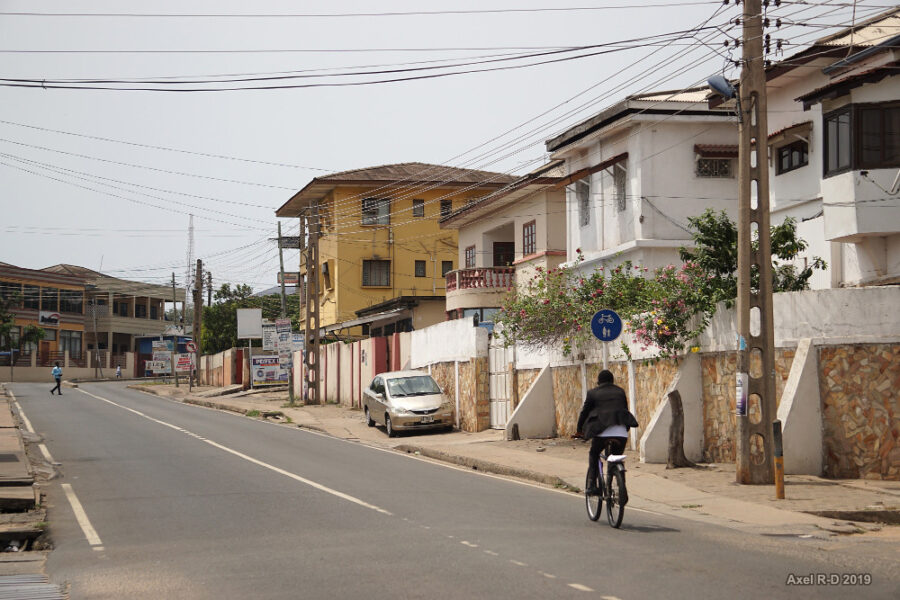 a cyclist rides through a street in Accra