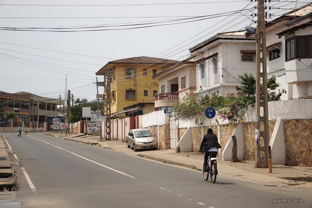 a cyclist rides through a street in Accra