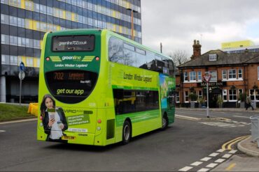 A green line coach station bus with a photo of a girl in the rear