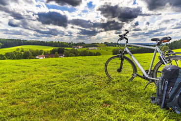 A backpack rests against a bicycle on a field