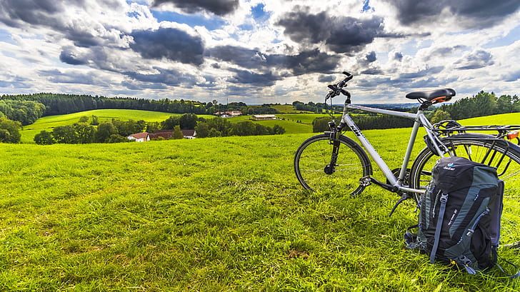 A backpack rests against a bicycle on a field