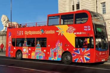 A tourist bus leaves a stop in London