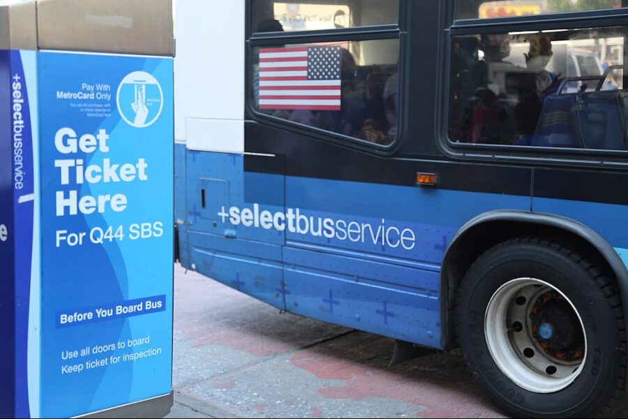 A SELECT BUS passes a stop in Queens, New York
