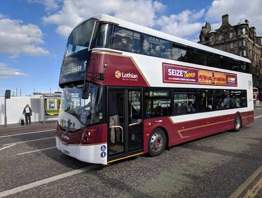 A Lothian bus parks near a building